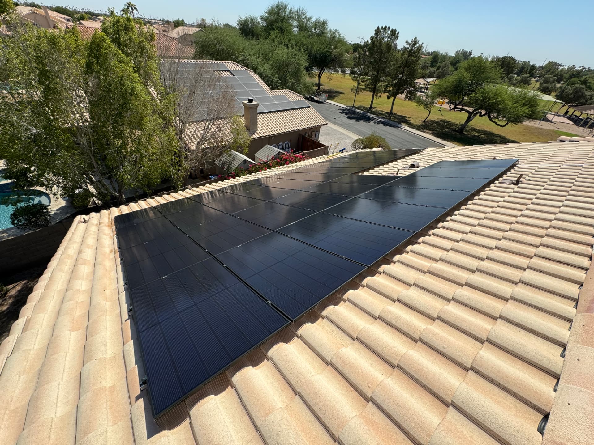 Clean solar array on a tan tile roof near a park