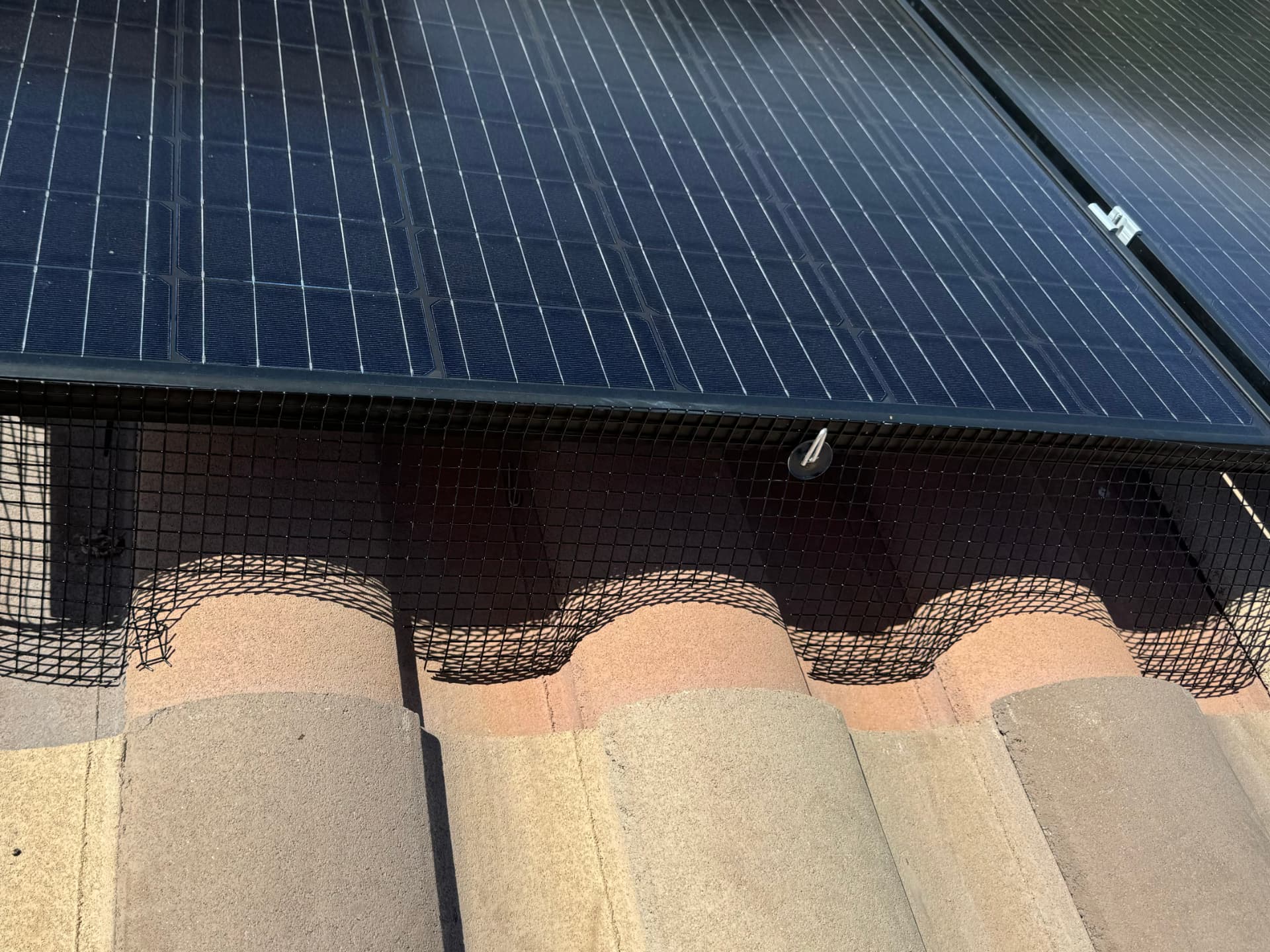 Close-up of mesh sealing the gap between solar panels and roof tiles
