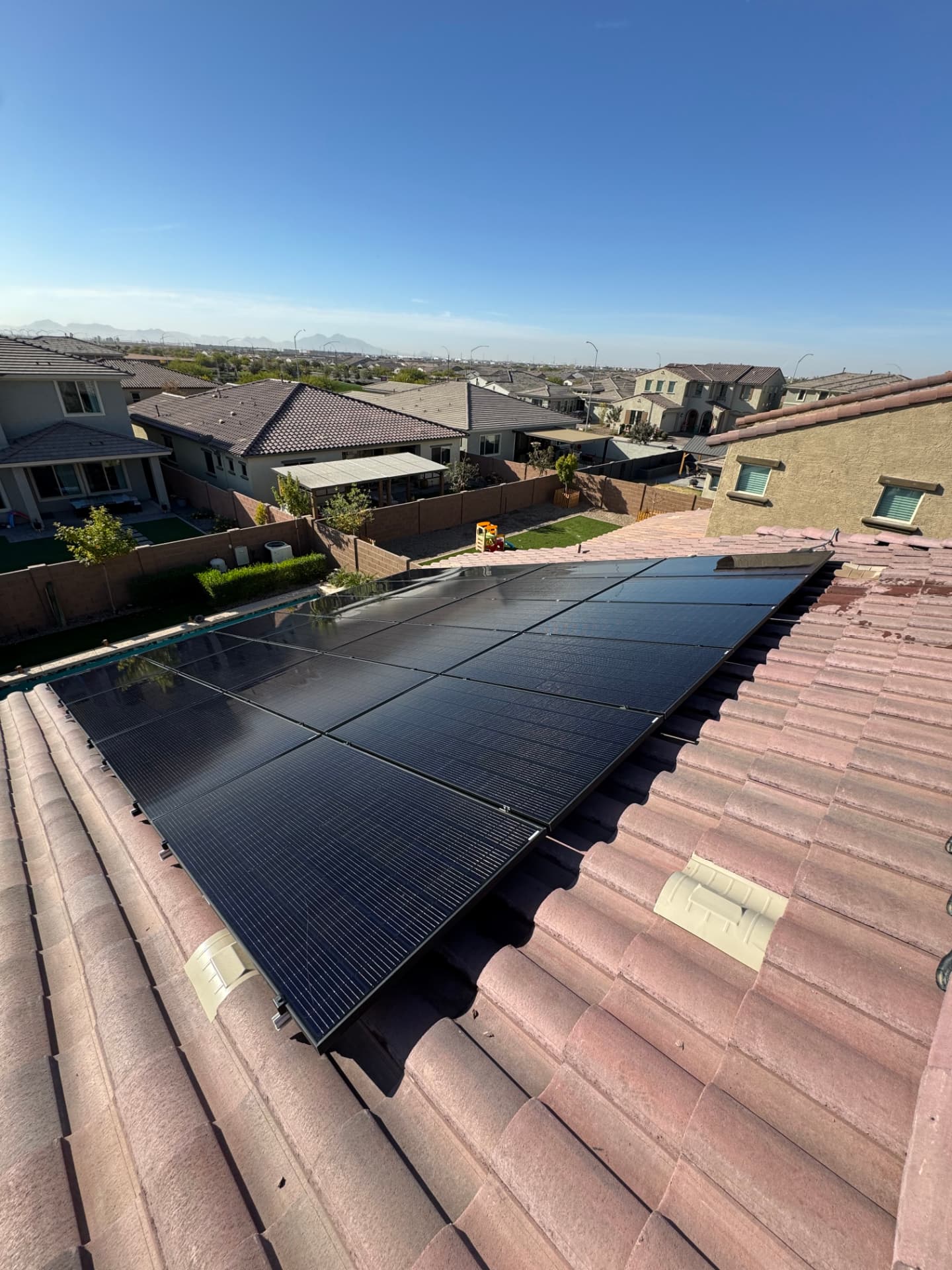 Clean black solar array along a tile roof ridge
