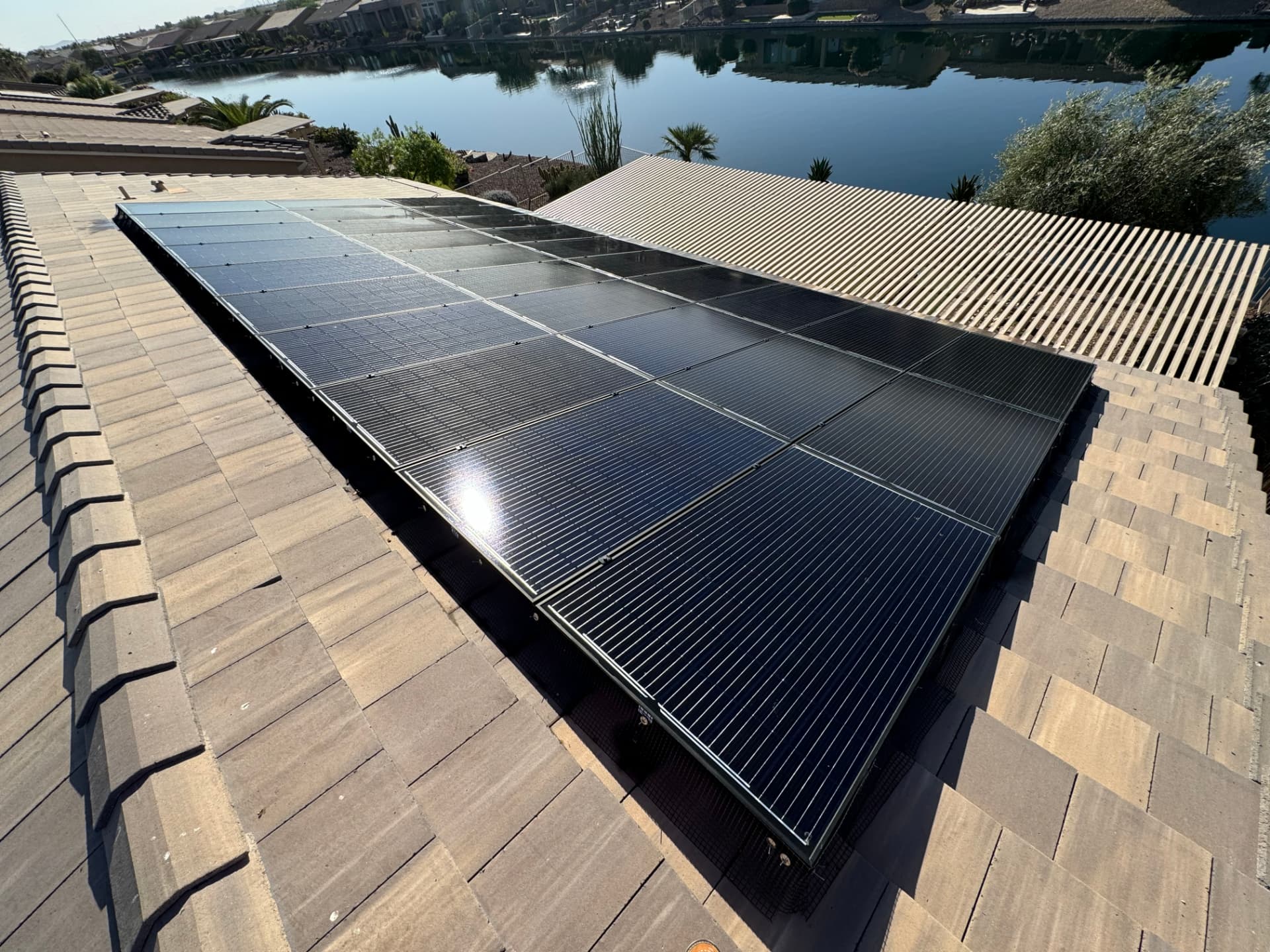 Spotless solar array on a tile roof beside a lake