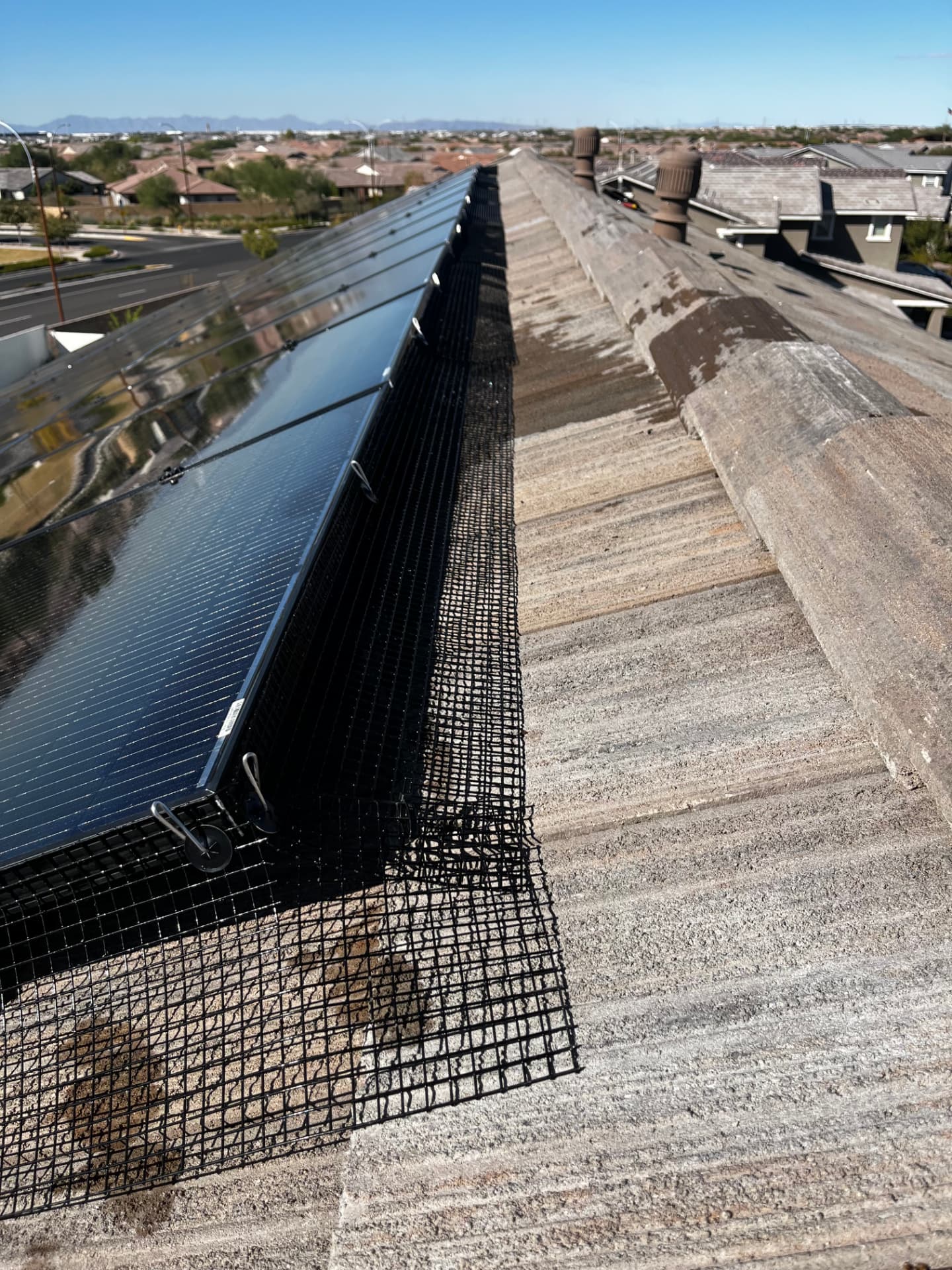 Finished pigeon barrier along a solar array on a tile roof
